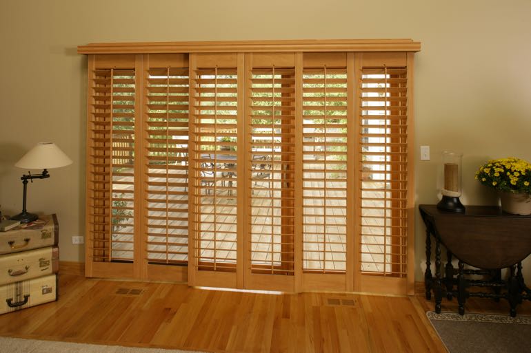 Faux wood shutters on sliding door leading to full porch.
